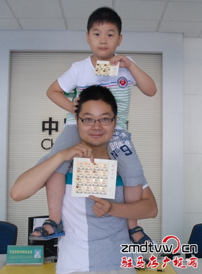 圖為6月13日，一對父子在市中心郵政所展示“感恩父親”特種郵票 .JPG