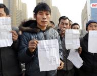 承建商已將工程款給付90%，但包工頭宋林卻把錢拿走不給工人結工資。一氣之下，十多名工人將包工頭車和人扣下，一不留神卻讓包工頭翻墻跑了。2015年12月31日，在勞動監(jiān)察部門協調下達成初步協議，包工頭將工人手續(xù)移交到成泰公司，由成泰公司替宋林代付一半工資，但在移交工人手續(xù)的時候包工頭害怕再次被扣卻一直不敢露面。1月3日，包工頭給農民工發(fā)來短信，并要求寫下承諾書，保證不扣他本人。圖為1月5日，陜西商洛，討薪農民工在工地上出示欠條和他們寫給包工頭的承諾書。華商報記者 閆文青/視覺中國