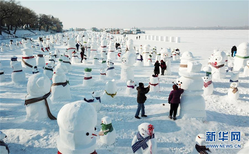 1月2日，市民、游客在雪人群中游玩觀賞（無人機(jī)拍攝）。2019個(gè)各式各樣的雪人，近日在冰城哈爾濱市的松花江畔亮相，引來眾多市民游客游玩觀賞。新華社記者 王建威 攝